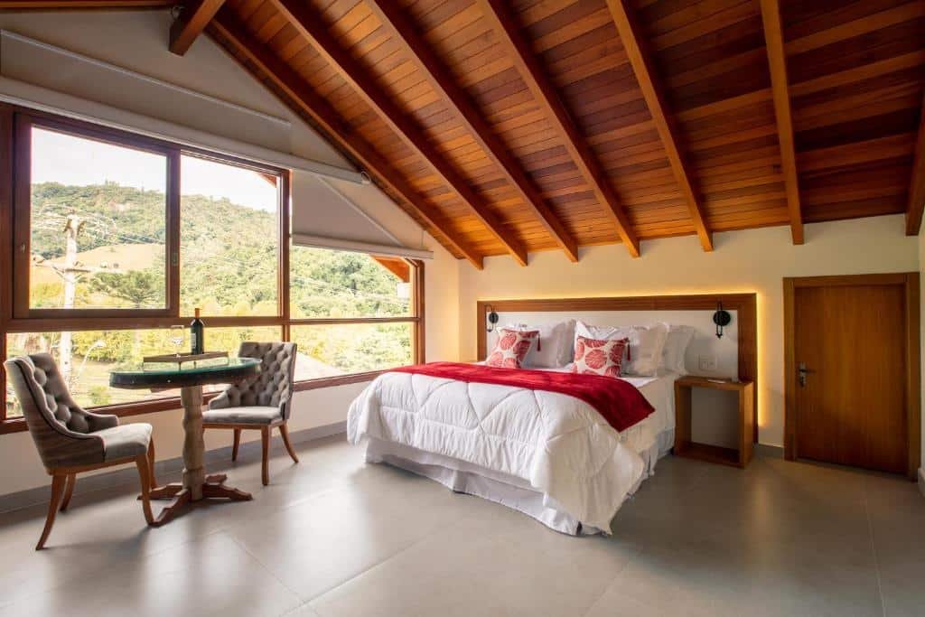 Quarto da Vinícola e Pousada Peculiare no Vale dos Vinhedos, com cama de casal ampla, mesinha e cadeiras